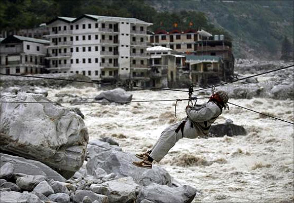 A man is pulled across to safety on a rope, as damaged buildings and the Alaknanda river are seen in the background, during a rescue operation in Govindghat in the Himalayan state of Uttarakhand.