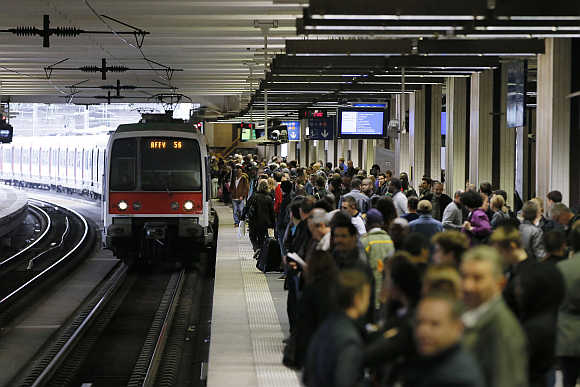 People wait on a platform as a commuter train arrives at the Gare du Nord railway station in Paris.