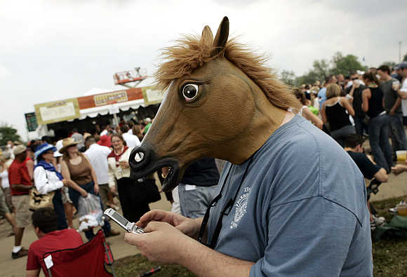 A spectator, wearing a mask in the shape of a horse's head, uses his mobile phone before the running of the Kentucky Derby at Churchill Downs in Louisville, Kentucky, United States.