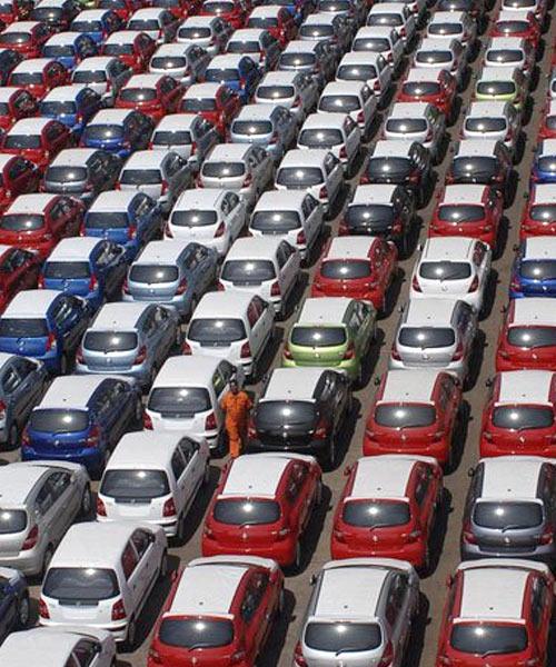 Workers walk beside cars ready for shipment at a harbour in Chennai.