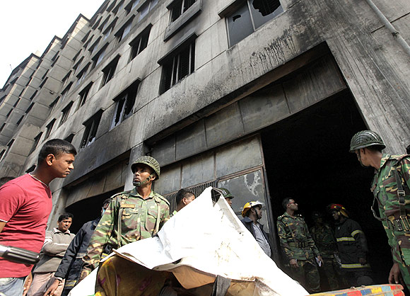  Army personnel load the body of a dead garment worker onto a rickshaw van after a devastating fire in a garment factory in Savar.