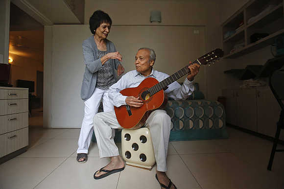 Aruna Gokhale, 81, watches as her husband Vidyadhar Gokhale, 84, plays guitar in their flat at the Athashri retirement village in Baner, on the outskirts of Pune.