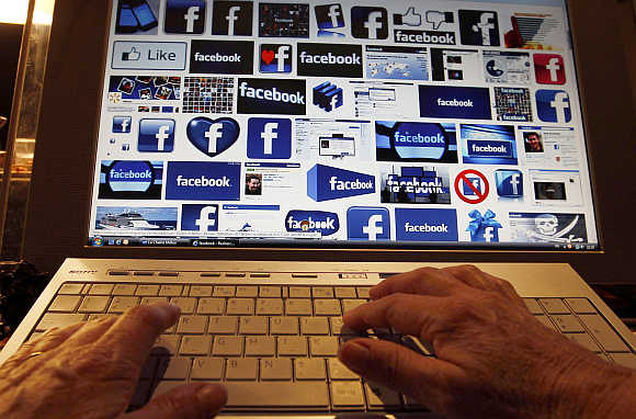A woman works on her computer which displays Facebook logos on the screen in Bordeaux, Southwestern France.