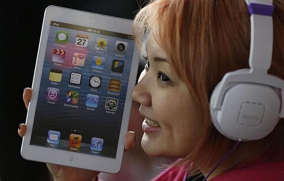 A woman holds a mock model of Apple's new iPad mini as she waits for the release of the tablet.