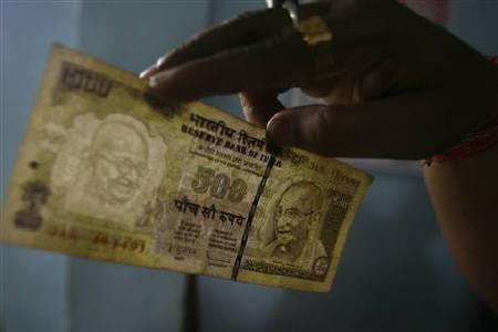 An employee checks a 500 rupee note at a cash counter inside a bank in Agartala.