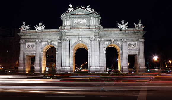 Traffic passes in front of the Alcala Gate, one of Madrid's famous landmarks in Spain.