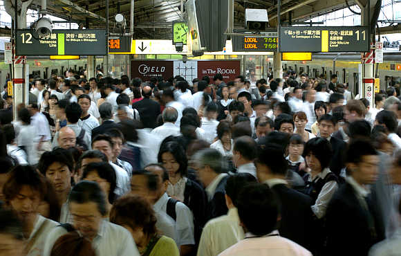 Commuters make their way to various destinations during rush hour at a train station in Tokyo, Japan.