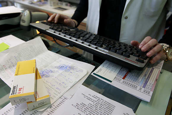 A pharmacist issues a receipt for a customer inside a pharmacy in Athens, Greece.