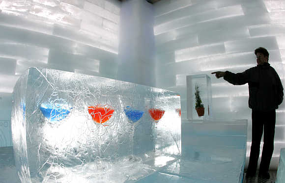 A visitor points to cocktail glasses inside a house constructed entirely of ice blocks as part of a promotion of a bank in Berlin, Germany.