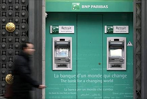 A man walks past an automatic teller outside a BNP Paribas bank in central Paris.