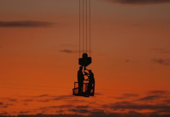 Labourers stand on a winch of a crane at a construction site on the outskirts of New Delhi.