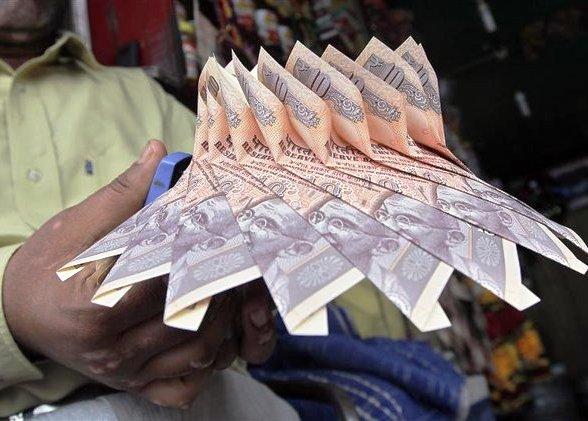 A Kashmiri shopkeeper staples together Indian currency notes to make a garland at a market in Srinagar.