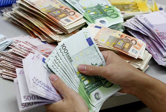 A bank employee counts euro notes at Kasikornbank in Bangkok, Thailand.