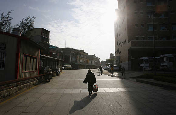A woman walks along a street at a market in Kinmen County. Kinmen, near Xiamen, China, is a small archipelago of several islands administered by Taiwan.