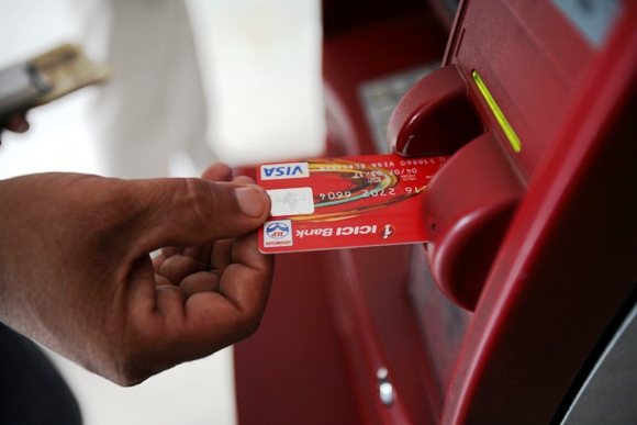 A customer uses his card to withdraw money from an ATM.
