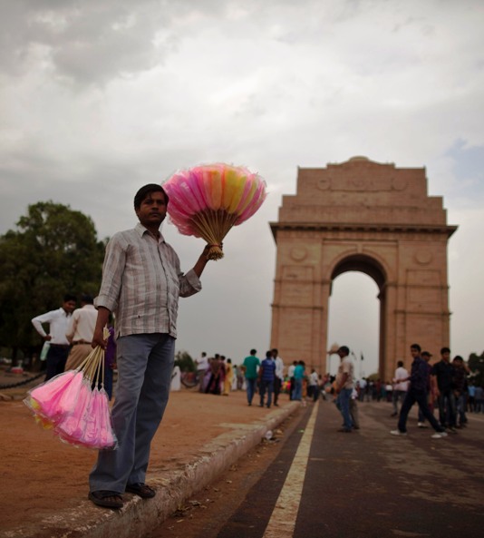 A vendor holds candies for sale in front of the India Gate against the backdrop of pre-monsoon clouds in New Delhi.