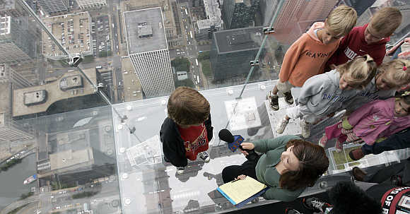 Ten-year-old Adam Kane, of Alton, Illinois, is interviewed by a television reporter as they stand on 'The Ledge', a five-sided glass box, 1,353 feet above the street in Chicago, United States.