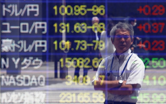 A passerby is reflected on a window displaying the Japanese yen's exchange rate against the US dollar (top) and other major foreign currencies outside a brokerage in Tokyo.