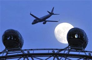 A passenger jet flies past the full moon.