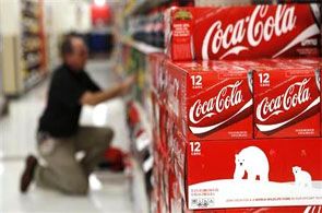 An employee arranges bottles of Coca-Cola at a store.