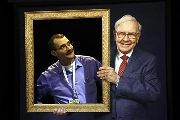 Richard Harmon (L), a Berkshire Hathaway shareholder, poses in an opening in a wall behind a picture frame held by a photograph of Berkshire Chairman Warren Buffet, at the company's annual meeting in Omaha.