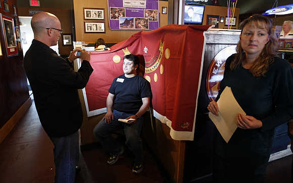 Mehdi Kaveh, left, a candidate for casino dealer position at Golden Casino Group has his picture taken by Jef Bauer, Vice-President and General Manager, during a job fair in the Spot tavern in Golden, Colorado, United States.
