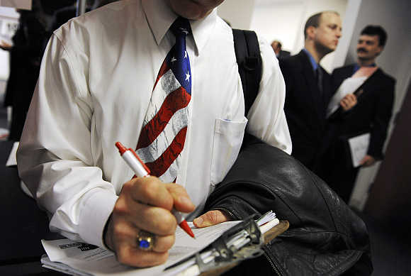 A man wearing a US flag necktie stands in line to talk to prospective employers at the National Capital Region Job Fair sponsored by Virginia Tech University at their branch campus in Falls Church, Virginia, United States.