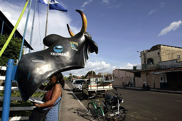 A tourist talks at a public phone booth fashioned to look like an ox, during the Parintins jungle carnival deep in the heart of the Amazon forest.