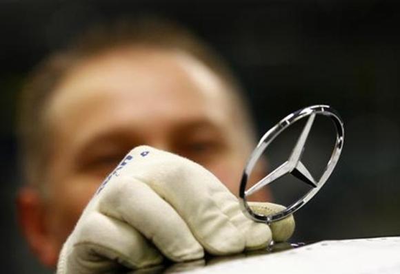 An employee of German car manufacturer Mercedes Benz installs the characteristic Mercedes star on the bonnet of a Mercedes S-class.