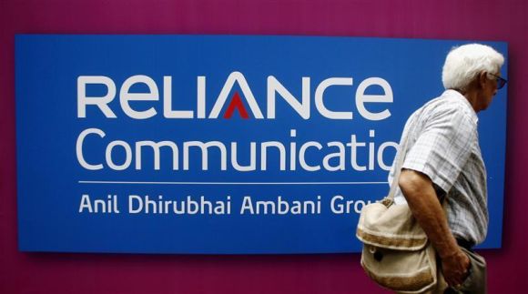 A man walks past a logo of Reliance Communication before the Annual General Meeting in Mumbai.