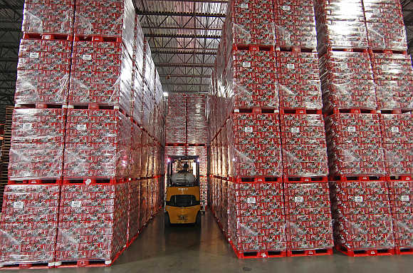 A worker drives a forklift between cases of Coca-Cola in a warehouse at the Swire Coca-Cola facility in Draper, Utah, United States.