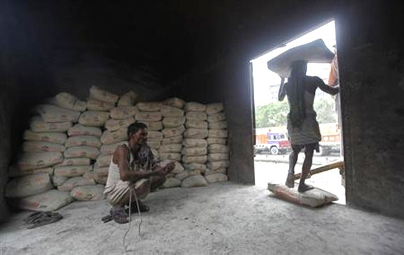 A labourer prepares chewing tobacco inside the wagon of a train as his colleague unloads cement sacks at a yard in Kolkata.