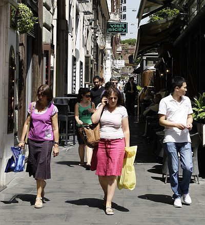 Shoppers walk past the Cafe De Paris on Via Veneto in Rome, Italy.