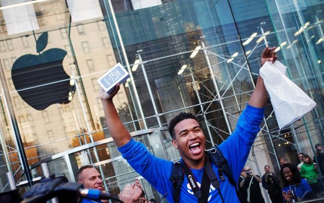 One of the first customers to purchase the Apple iPhone 5S celebrates after exiting the Apple Retail Store on Fifth Avenue in Manhattan, New York.