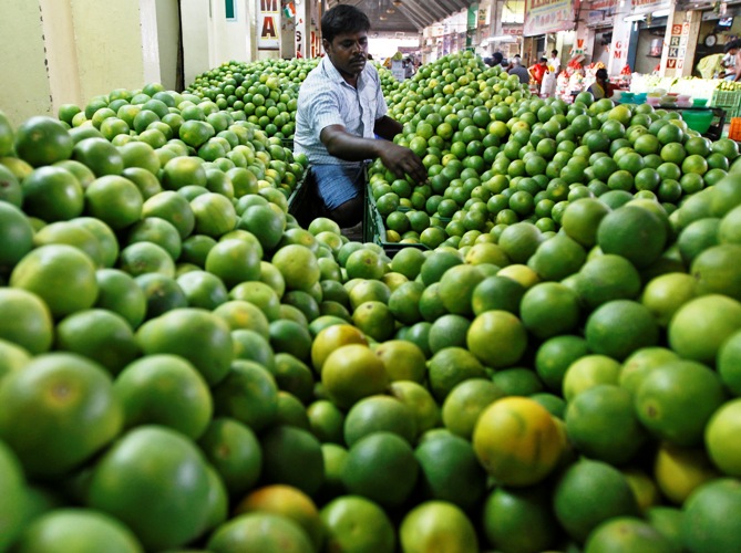 A vendor arranges sweet limes at his shop at a wholesale fruit market in Chennai.