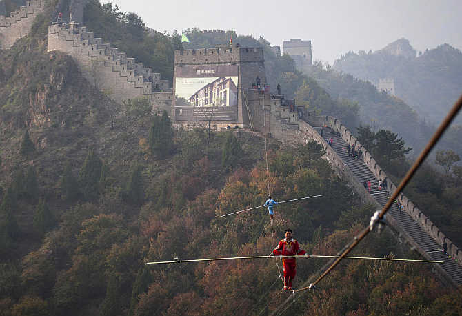 Adili Wuxor, front, who is known as 'Prince of the Tightrope', and his apprentice walk on a tightrope above the Great Wall in Tianjin, China.