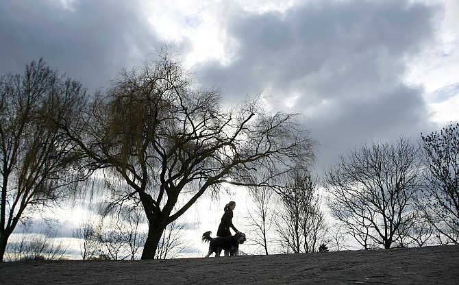 A woman walks with her dog on a dyke along the Weser River in Bremen, Germany.