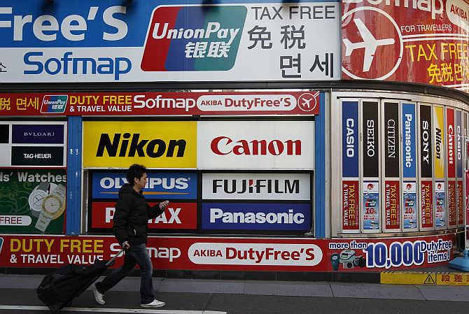 A man walks past an advertisement board at the electronic shopping district Akihabara in Tokyo, Japan.