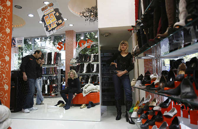 A salesperson watches as a woman tries on a pair of shoes in Tel Aviv, Israel.