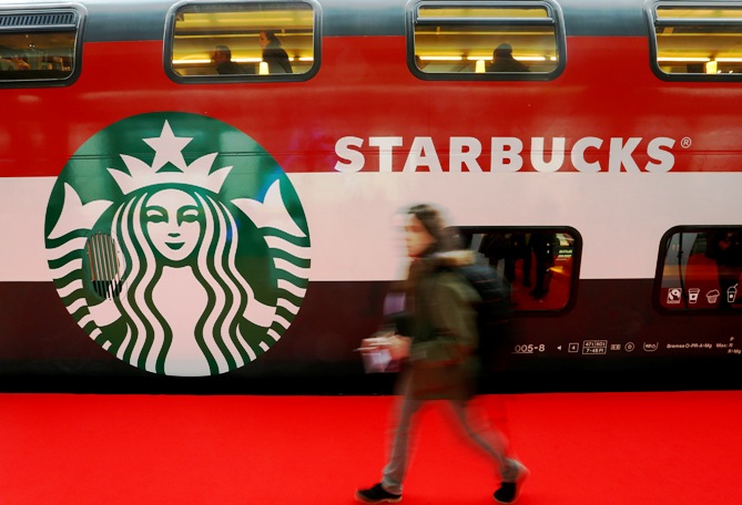 A woman walks past a Starbucks logo painted on a railway coach at the main train station in Zurich.
