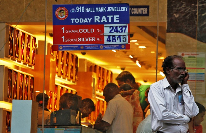 A man speaks over his mobile phone as customers buy gold at a jewellery showroom in Chennai.