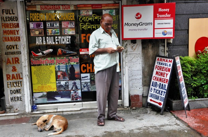 A customer counts currency outside a currency exchange shop in Kolkata.
