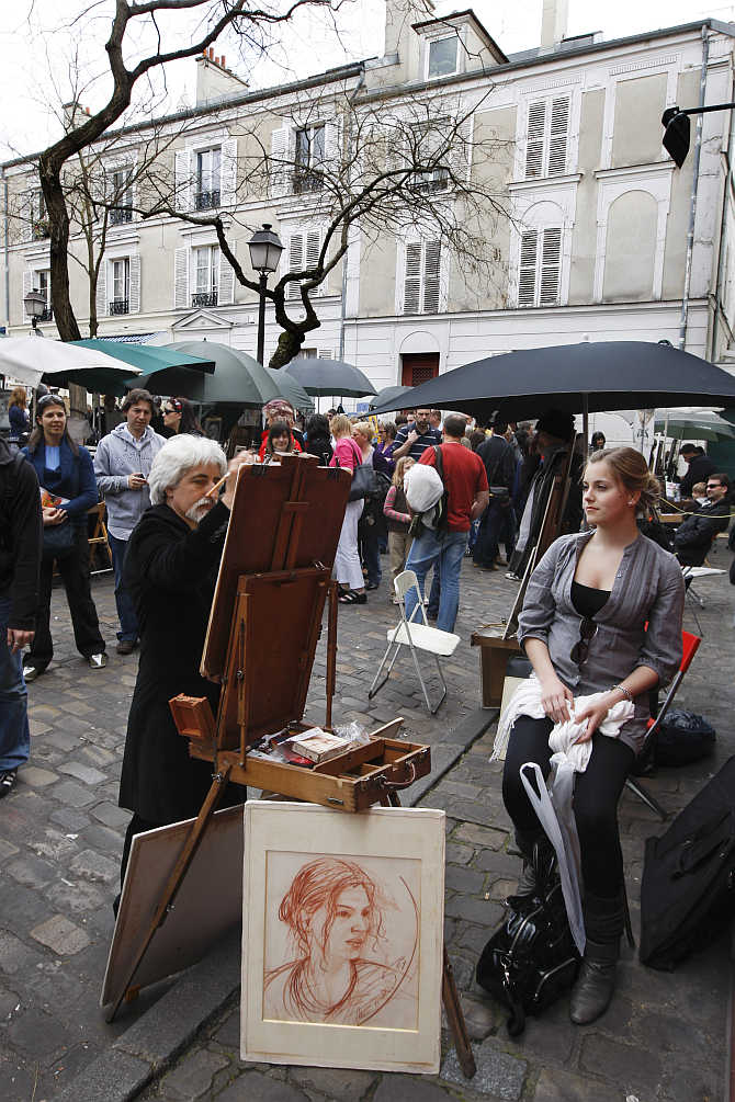 A tourist is portraiyed by an artist in the former village of Montmartre near the Sacre Coeur Basilica in Paris, France.