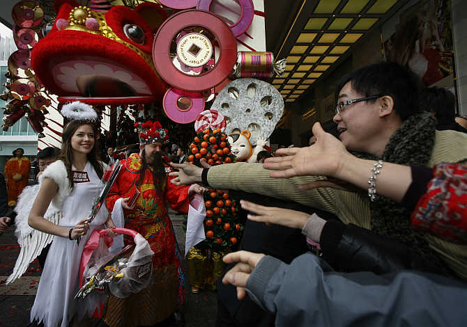 Models dressed as Cupid and the Chinese God of Wealth offer roses and souvenirs outside a shopping mall in Hong Kong.