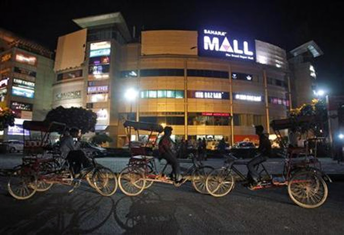 Rickshaw pullers wait for customers outside the Sahara Mall, a shopping centre built by Sahara group, in Gurgaon