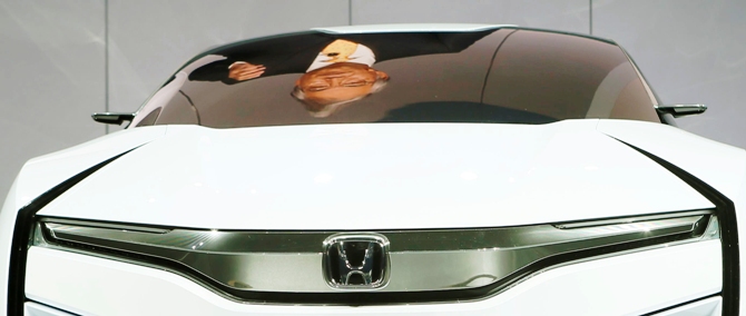 Tetsuo Iwamura, president and CEO of American Honda Motor Co., is reflected on the Honda FCEV Concept car during the 2013 Los Angeles Auto Show, California.