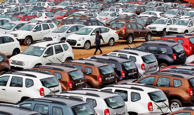 A worker walks past parked Renault cars at its stockyard on the outskirts of Ahmedabad.
