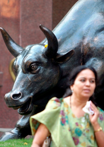 A woman walks past a bronze replica of a bull at the Bombay Stock Exchange building in Mumbai.