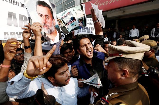 Activists of the Akhil Bharatiya Vidyarthi Parishad, linked to Bharatiya Janata Party, hold posters of Tarun Tejpal and shout slogans as police try to stop them during a protest in New Delhi, November 22, 2013.