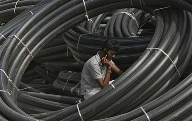 A construction supervisor speaks on a mobile phone amid rolls of underground telephone cable pipes.